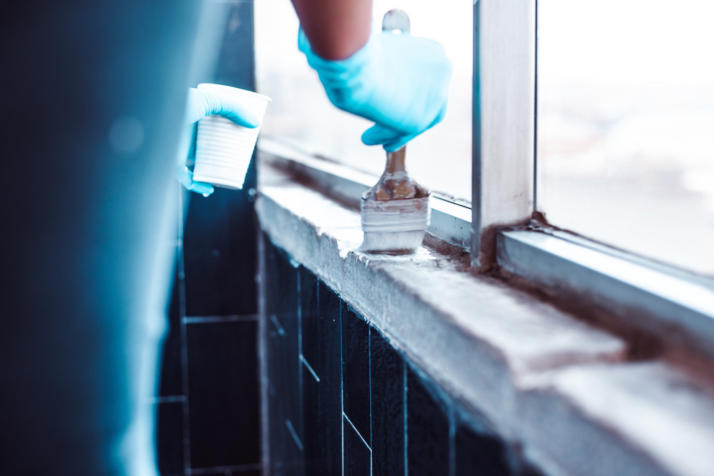 Hands in Gloves Painting a White Wall